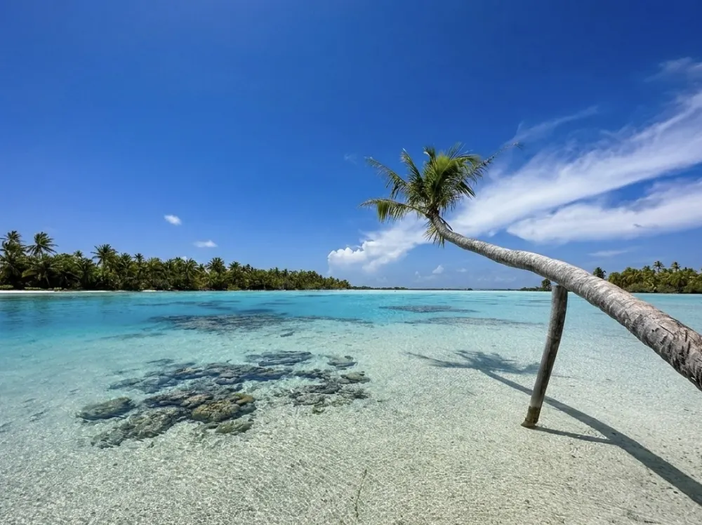 Crystal clear Blue Lagoon with white sand motu in Fakarava