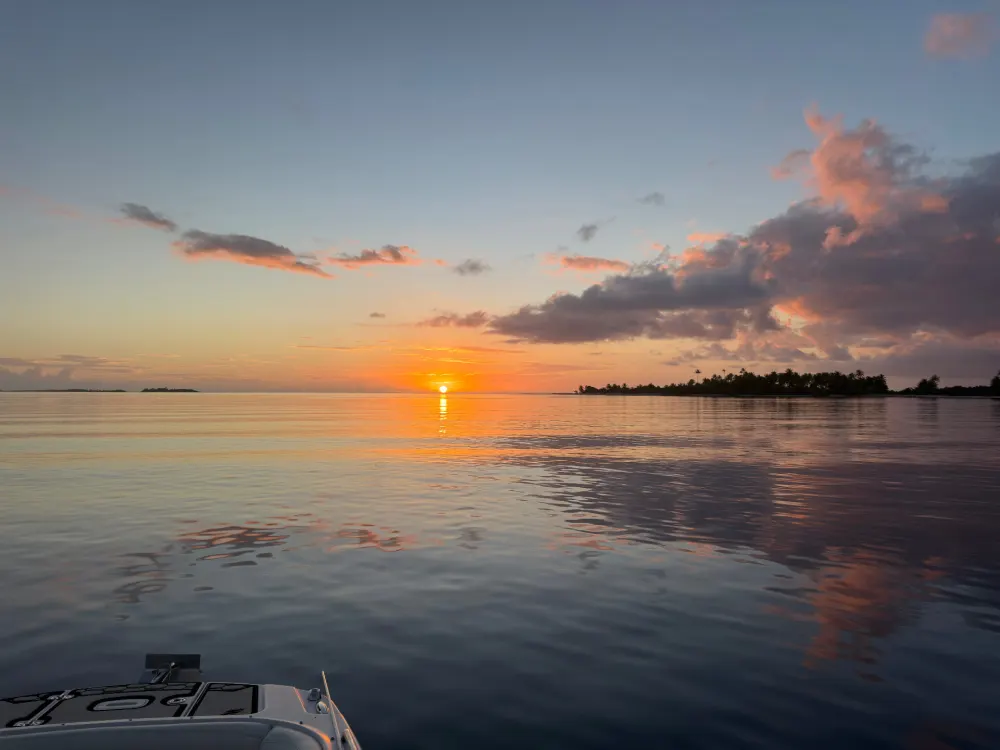 Golden sunset over Fakarava lagoon with boat silhouette